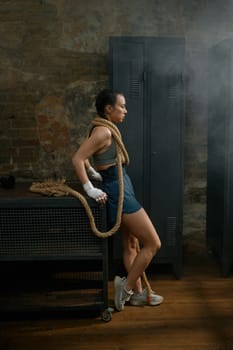 Fashion gorgeous woman boxer wrapped in rope on loft gym background. Boxing concept