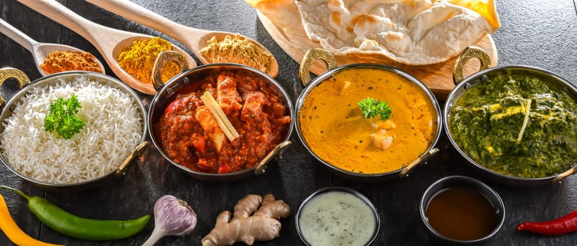 Composition with indian dishes: madras paneer, palak paneer and shahi paneer with basmati rice served in original indian karahi pots.