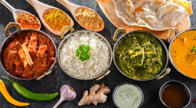 Composition with indian dishes: madras paneer, palak paneer and shahi paneer with basmati rice served in original indian karahi pots.