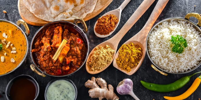 Composition with indian dishes: madras paneer, palak paneer and shahi paneer with basmati rice served in original indian karahi pots.