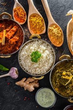 Composition with indian dishes: madras paneer, palak paneer and shahi paneer with basmati rice served in original indian karahi pots.