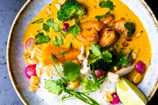Thai chicken and a peanut curry with rice, dark background, top view. Asian cuisine concept.