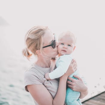 Tender woman caressing her little baby boy infant child outdoors. Mother's unconditional love for her child.