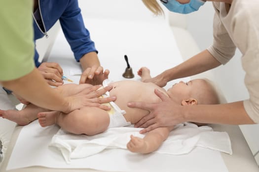 Baby beeing vaccinated by pediatrician in presence of his mother. Preventive vaccination against Diphtheria, whooping cough, tetanus, hepatitis, haemophilus influenzae, pneumococcus, poliomyelitis.
