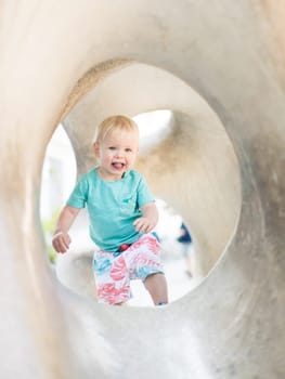 Child playing on outdoor playground. Toddler plays on school or kindergarten yard. Active kid on stone sculpured slide. Healthy summer activity for children. Little boy climbing outdoors