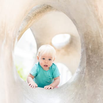 Child playing on outdoor playground. Toddler plays on school or kindergarten yard. Active kid on stone sculpured slide. Healthy summer activity for children. Little boy climbing outdoors