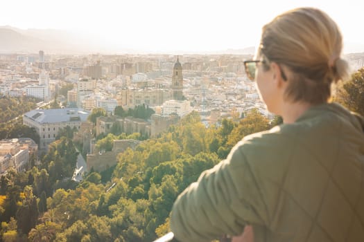Bolnde female touris enjoying amazing panoramic aerial view of Malaga city historic center, Coste del Sol, Andalucia, Spain.