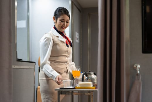 In flight service. Air hostess or cabin crew working in airplane. Female flight attendant preparing food and drinks for passengers on board. Airline transportation and tourism concept.