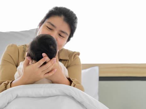 Baby head in mother hands. Happy asian mom sitting and nursing infant baby on bed. Love, Health Care and mothers day concept