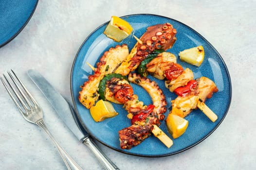 Skewers of octopus and squid on plate. Grilled octopus tentacle. Sea delicacy.