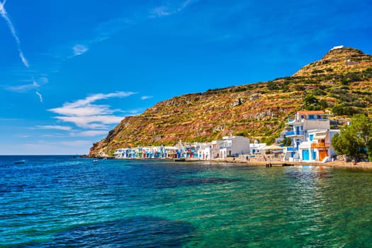 Colorful village of Klima with Greek whitewashed houses on sunny day, Milos island, Cyclades, Greece. Traditional fishermen village, bright painted and weathered doors and doorways, high hill, great blue sky, azure sea, summer sunshine, vacations.