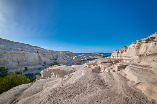 Famous white rocks of Sarakiniko beach, Aegean sea, Milos island , Greece. No people, empty cliffs, summer day sunshine, beautiful landscape, blue sky and clouds, fantastic gorge, tourist destination.