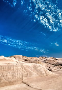 Beautiful rocks of Sarakiniko beach, Aegean sea, Milos island , Greece. No people, empty cliffs, summer day sunshine, lunar landscape, fantastic rocks of tourist destination, deep blue sky, clouds, vertical shot