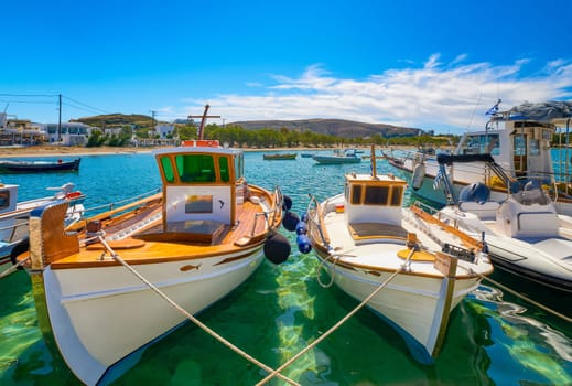 Beautiful view of Greek fishing boats anchored in a small village. Summer day sunshine, island, village, town, whitewashed houses, colorful fishing boats, Mediterranean lifestyle, green hills, vacations, relax, travel destinations. Milos, Greece.