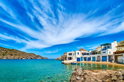 Beautiful small fishing village, traditional white fishermen houses and boat garages, turquoise clear sea water and blue sky. Firoporamos or Fyropotamos, Milos island, Cyclades, Greece. Perfect summer vacations site.