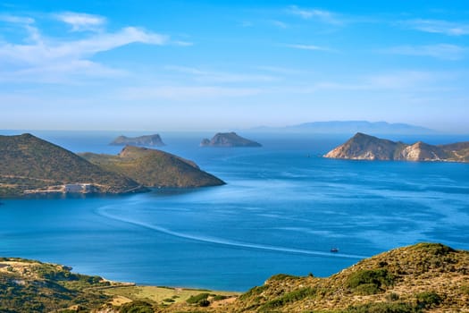 Beautiful landscape with several islets in bay, distant hazy shores, blue sea waters, great sky, sunny summer day in Mediterranean sea. Picturesque harbour, perfect Greek travel and vacation. Milos island, Greece.
