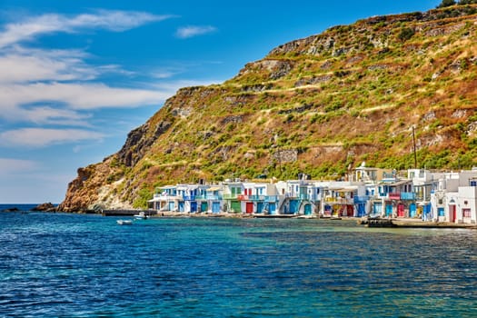 Colorful village of Klima with Greek whitewashed houses on sunny day, Milos island, Cyclades, Greece. Traditional fishermen village, bright painted and weathered doors and doorways, high hill, great blue sky, azure sea, summer sunshine, vacations.