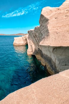 Famous white rocks of Sarakiniko beach, Aegean sea, Milos island , Greece. No people, empty cliffs, summer day sunshine, clear sea, blue waters, clear sky, cyan-pink colors, beautiful landscape, fantastic rocks of tourist destination. Vertical shot