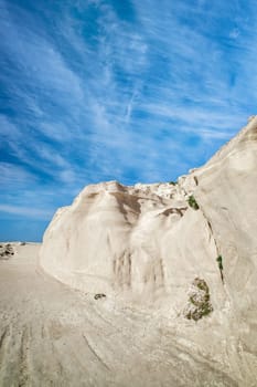 Beautiful white rocks of Sarakiniko beach, Aegean sea, Milos island , Greece. No people, empty cliffs, summer day sunshine, lunar landscape, fantastic rocks of tourist destination, deep blue sky, clouds, vertical shot