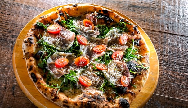 Pizza Italiana served with ham, cheese, tomatoes and rucola.