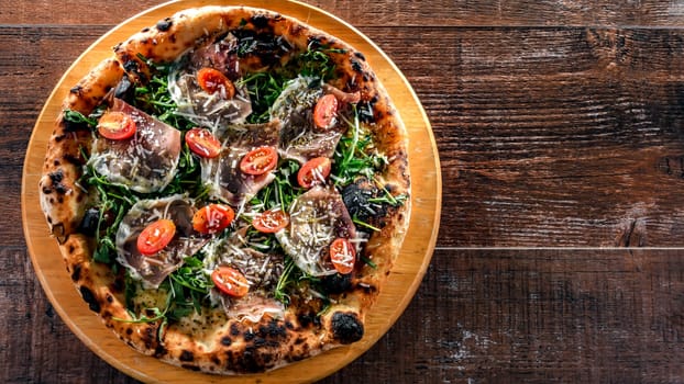 Pizza Italiana served with ham, cheese, tomatoes and rucola.
