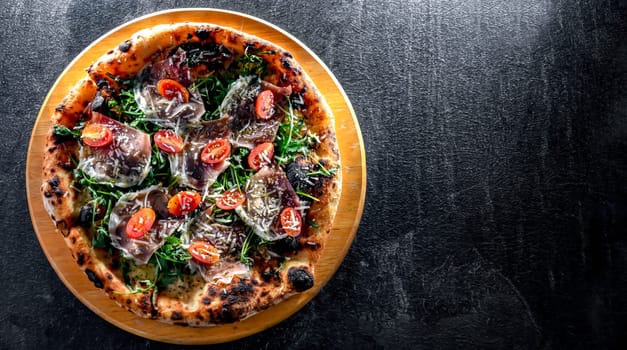 Pizza Italiana served with ham, cheese, tomatoes and rucola.