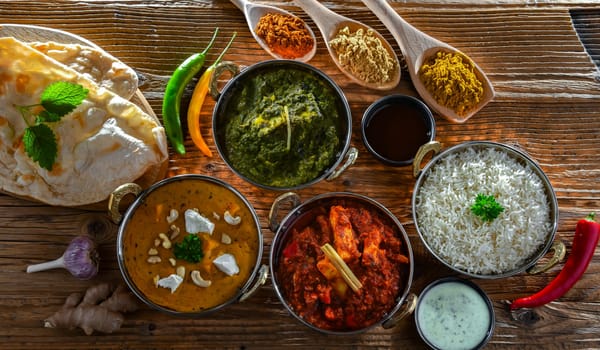 Composition with indian dishes: madras paneer, palak paneer and shahi paneer with basmati rice served in original indian karahi pots.