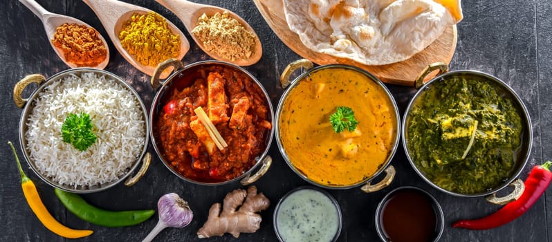 Composition with indian dishes: madras paneer, palak paneer and shahi paneer with basmati rice served in original indian karahi pots.