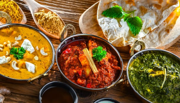 Composition with indian dishes: madras paneer, palak paneer and shahi paneer with basmati rice served in original indian karahi pots.