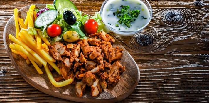 Kebab served with french fries, vegetable salad and tzatziki