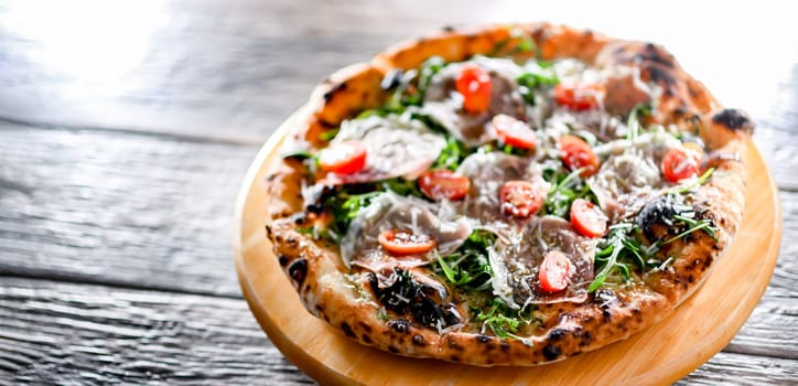 Pizza Italiana served with ham, cheese, tomatoes and rucola.