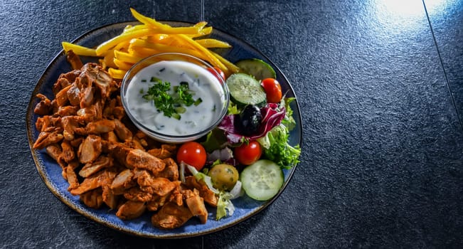 Kebab served with french fries, vegetable salad and tzatziki