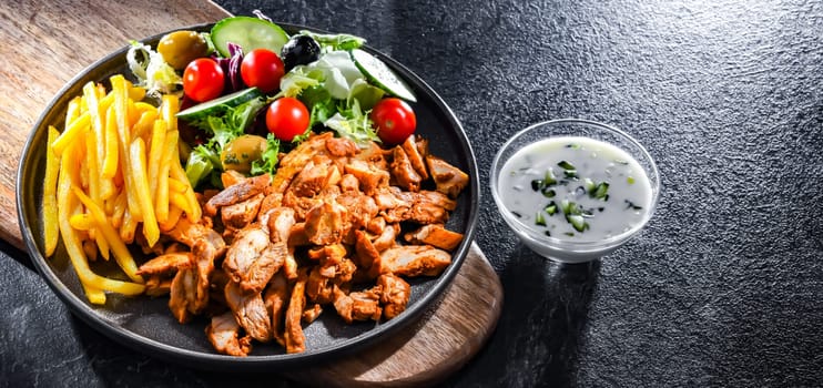Kebab served with french fries, vegetable salad and tzatziki