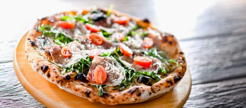 Pizza Italiana served with ham, cheese, tomatoes and rucola.