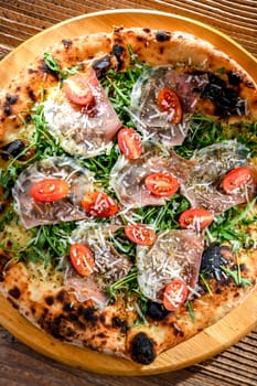 Pizza Italiana served with ham, cheese, tomatoes and rucola.