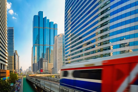 BTS Skytrain, light metro electric train, running fast in downtown, Bangkok, Thailand. Motion blur effect, modern office buildings, condominiums, business center, BTS rapid transit system, public transport, motion blur effect.