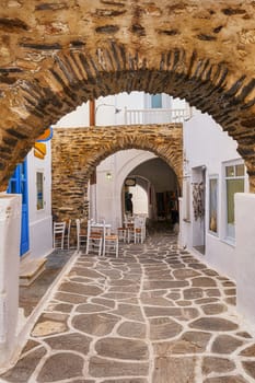 Old narrow alleyways of Greek towns, Medieval arches and streets, whitewashed walls, stone pavement, cozy cafes, bars and restaurants, craft shops, perfect place for tourist stroll, shop and enjoy their vacations. Naoussa, Paros island, Greece.