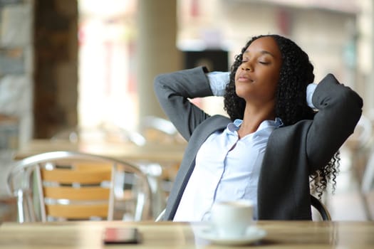 Black busineswoman resting sitting in a coffee shop terrace