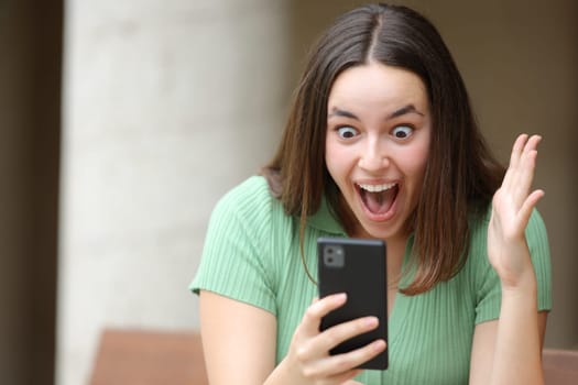 Excited woman checking amazing content on phone in the street