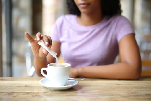 Close up of a black woman throwing sugar in a coffee cup in a bar terrace