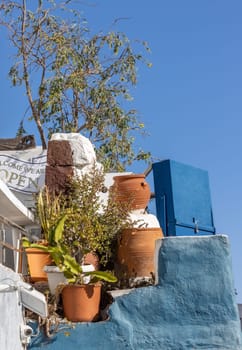 Oia, Santorini, Greece - June 28, 2021: Flower pots on a blue background in Oia, Santorini. Greece