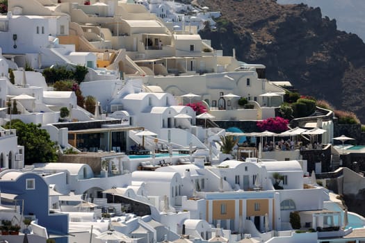 Oia, Santorini, Greece - July 3, 2021: Whitewashed houses with terraces and pools and a beautiful view in Oia on Santorini island, Greece