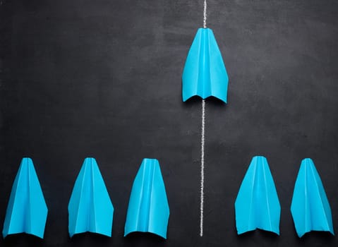 A group of paper blue airplanes with one leading ahead, concept of a strong leader.