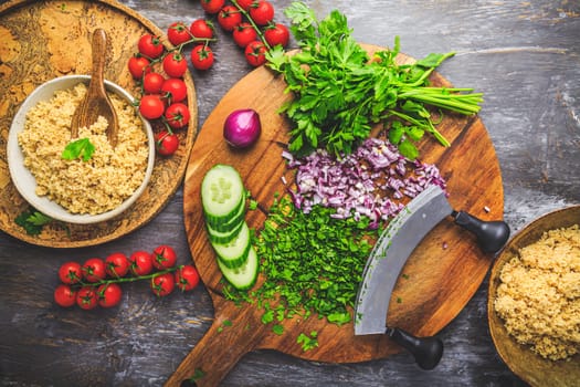 Preparing traditional oriental salad Tabouleh with couscous or bulgur, ingredients on cutting board
