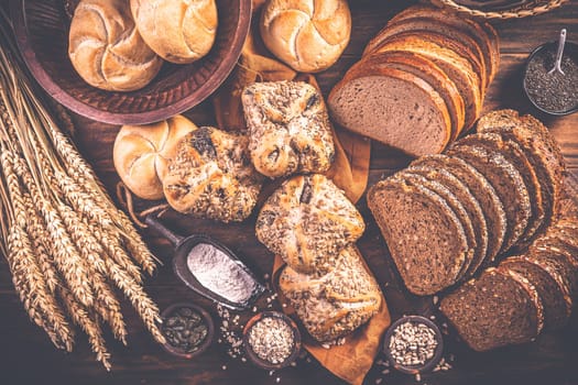 Assortment of different kind of cereal bakery - bread, pasties, buns, with healthy seeds on wooden background