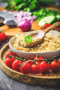 Preparing traditional oriental salad Tabouleh with couscous or bulgur, ingredients on cutting board