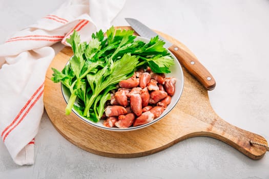 Fresh raw chicken hearts with celery leaves, reading for cooking