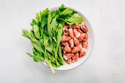 Fresh raw chicken hearts with celery leaves, reading for cooking