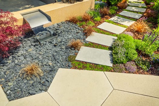 Detail of garden path with stone slabs with bark mulch and native plants. Landscaping and gardening concept.
