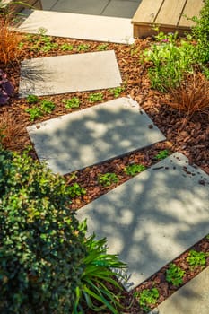 Detail of garden path with stone slabs with bark mulch and native plants. Landscaping and gardening concept.